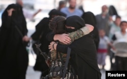 FILE - A woman embraces a Syrian Democratic Forces (SDF) fighter after she was evacuated with others by the SDF from an Islamic State-controlled neighborhood of Manbij, in Aleppo governorate, Syria, Aug. 12, 2016.