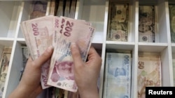FILE - A money changer counts Turkish lira bills at an currency exchange office in central Istanbul, Turkey, Aug. 21, 2015.