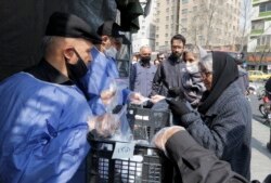 People queue in line to receive packages for precautions against COVID-19 coronavirus disease outside Meydane Valiasr metro station in Tehran, March 15, 2020.