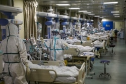 FILE - Medical workers in protective suits attend to novel coronavirus patients at the intensive care unit of a designated hospital in Wuhan, Hubei province, China, Feb. 6, 2020.