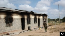 A member of Kenya's security forces walks past a damaged police post after an attack by al-Shabab extremists in the settlement of Kamuthe in Garissa County, Kenya, Jan. 13, 2020. 