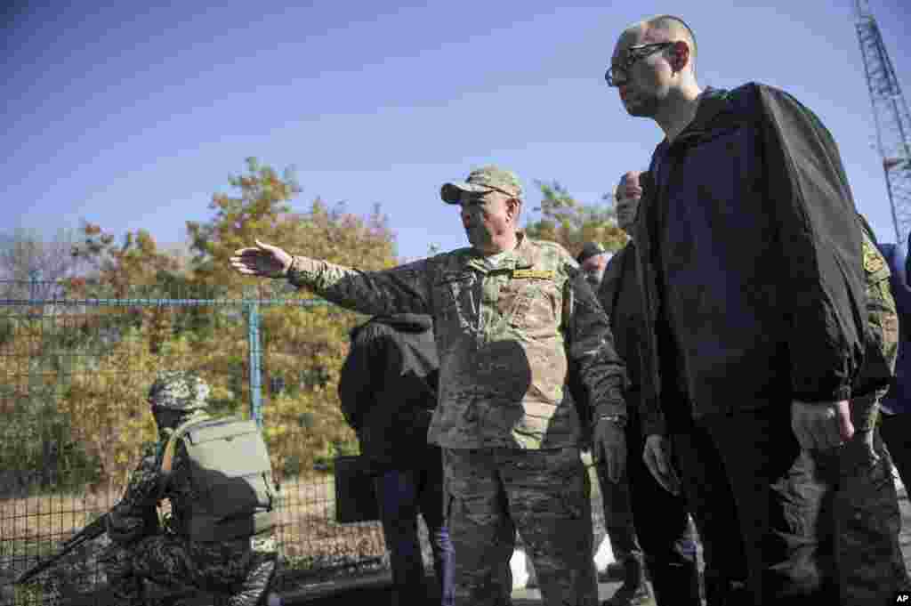 Ukrainian Prime Minister Arseniy Yatsenyuk, right, inspects part of Ukraine's eastern border with Russia close to Kharkiv, Ukraine, Oct. 15, 2014.