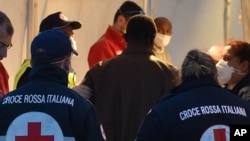 A migrant waits to undergo a medical check near the harbor after disembarking from Italian Coast Guard ship "Dattilo," in Augusta's port, near Siracusa, Sicily, April 16, 2015.