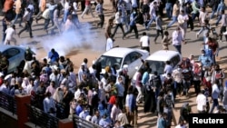 FILE - Sudanese demonstrators run from tear gas lobbed to disperse them as they march along the street during anti-government protests in Khartoum, Sudan, Dec. 25, 2018.