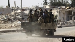 Des rebelles passent des bâtiments en ruine à al-Rai town, au nord d'Alep, Syrie, le 2 octobre 2016. 