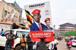 A supporter of Ugandan opposition Presidential candidate Robert Kyagulanyi also known as Bobi Wine, carry his electoral campaign poster ahead of the presidential and parliamentary elections, in Kampala, Uganda, Jan. 12, 2021.