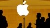 FILE - Customers walk past an Apple logo inside of an Apple store at Grand Central Station in New York, Aug. 1, 2018.