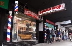 Men queue for a haircut outside a barber shop in Melbourne, Oct. 19, 2020. (AFP)