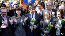Former Catalan leader Carles Puigdemont, center, holds a bunch of flowers as he and supporters sing after a news conference in Berlin, Germany, Saturday, April 7, 2018.