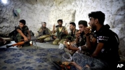 FILE - Syrian rebels eat in a cave in which they also live, on the outskirts of the northern town of Jisr al-Shughur, Idlib province, Syria, west of the city of Idlib, Sept. 9, 2018.