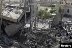Houthi militants gather on the rubble of the offices of the education ministry's workers union, destroyed by Saudi-led airstrikes, in Yemen's northwestern city of Amran, August 19, 2015.