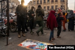 Slika palog diktatora Bashara al-Assada prikazana je na trotoaru u Damasku u Siriji, a stanovnici je prelaze kako bi pokazali svoj bijes protiv režima, dok vojnici HTS-a gledaju, 12. decembar 2024.