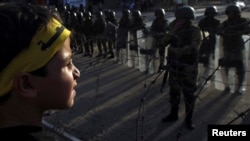 Seorang bocah laki-laki dan para pendukung Ikhwanul Muslimin dan presiden tersingkir Mohamed Morsi, berdiri di depan tentara dan polisi dalam sebuah protes di Kairo (4/10). (Reuters/Amr Abdallah Dalsh)