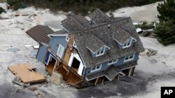 FILE - This Oct. 31, 2012 file aerial photo shows a collapsed house along the Jersey Shore coast. A recent poll shows that a clear majority of mayors are prepared to confront President Donald Trump's administration over climate change.