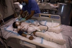 A medic treats a wounded girl in the intensive care unit of the Shifa hospital, May 13, 2021, in Gaza City. She was injured by a May 12 Israeli strike that hit her family's home.
