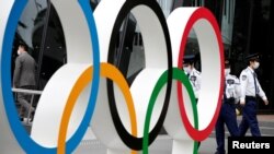 Security personnel stand guard near the Olympic rings monument during a rally by anti-Olympics protesters outside the Japanese Olympic Committee headquarters in Tokyo, Japan, May 18, 2021. 