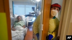 FILE - Registered nurse Rachel Chamberlin steps out of an isolation room where Fred Rutherford recovers from COVID-19 at Dartmouth-Hitchcock Medical Center, in Lebanon, N.H., Jan. 3, 2022.