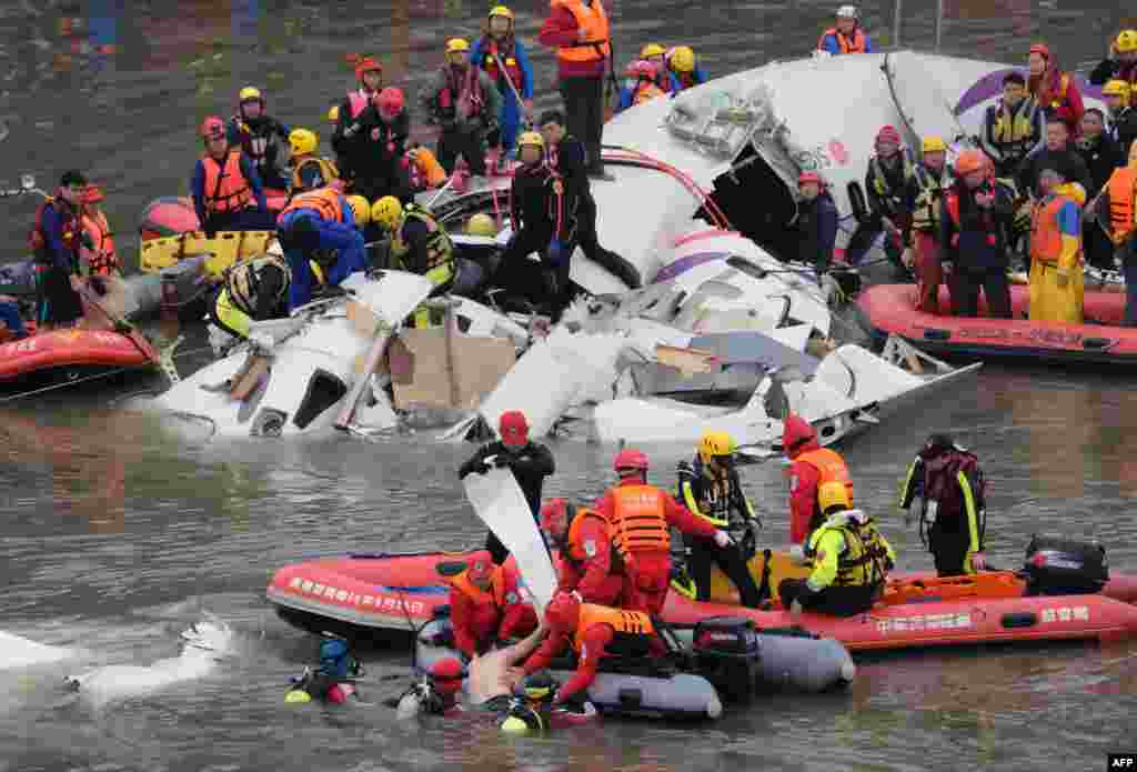 Rescue personnel in a rubber dinghy lift a passenger (bottom C) from the waters around the wreckage of a TransAsia ATR 72-600 turboprop plane that crash-landed into the Keelung river outside Taiwan&#39;s capital Taipei in New Taipei City.