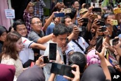 Calon wakil presiden yang juga putra sulung Presiden Joko Widodo Gibran Rakabuming Raka, tengah, berbincang dengan pendukungnya usai mencoblos di TPS Solo, 14 Februari 2024. (Foto: AP)