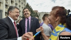 FILE - Ukrainian President Petro Poroshenko (L) and governor of Odessa region Mikheil Saakashvili (C) are greeted by a local resident near the regional state administration in Odessa, May 30, 2015.