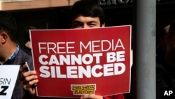 FILE - A protester is seen holding a placard at a rally in support of press freedom near the headquarters of a media company in Istanbul, Oct. 28, 2015.