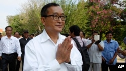Cambodian main opposition Cambodia National Rescue Party leader Sam Rainsy, front, greets his supporters as his arrives at Choeung Ek memorial on the outskirts of Phnom Penh, Cambodia, Friday, May 17, 2015. 