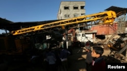 Palestinians inspect the scene of what witnesses said was an air strike on a workshop in Gaza City, May 5, 2016.