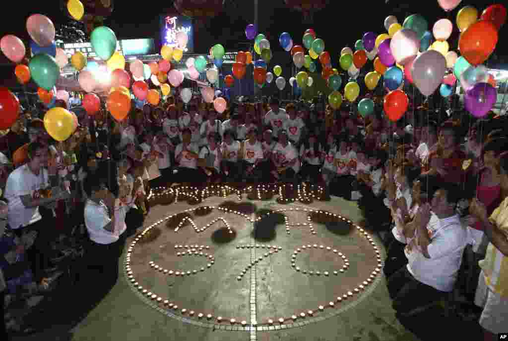 Orang-orang memegang balon dekat pesan yang bertuliskan &quot;Doa untuk MH370&quot; (17/3). (AP/Lai Seng Sin)&nbsp;
