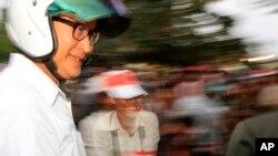 Cambodian opposition leader Sam Rainsy of the Cambodia National Rescue Party wearing a helmet arrives for a rally in Phnom Penh, Cambodia, Monday, Dec. 16, 2013. The opposition party rallied for the second day, calling for Prime Minister Hun Sen's government to hold re-election. (AP Photo/Heng Sinith)
