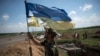 Український солдат встановлює прапор України на українських позиціях у Мар'їнці під Донецьком, 5 червня 2015 