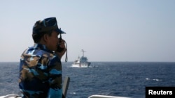 FILE - An officer of the Vietnamese coast guard officer speaks on a radio as he monitors a Chinese vessel in the South China Sea. Along with fishing and lucrative shipping routes, oil and gas reserves are often cited as a major reason for the disagreements over which country owns which patch of water.