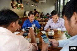 រូបឯកសារ៖ បុរសមួយក្រុមកំពុងប្រើប្រព័ន្ធអ៊ីនធឺណិតតាមទូរស័ព្ទទំនើបរបស់ពួកគេ នៅក្នុងហាងកាហ្វេមួយ នៅរាជធានីភ្នំពេញ កាលពីថ្ងៃទី១៧ ខែតុលា ឆ្នាំ២០១៨។