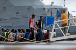 FILE - A police officer speaks to rescued migrants after they arrived on an Armed Forces of Malta patrol boat in Valletta's Marsamxett Harbor, Malta, Sept. 21, 2019.