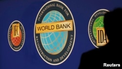 FILE - A man is silhouetted against the logo of the World Bank at the main venue for the International Monetary Fund (IMF) and World Bank annual meeting in Tokyo October 10, 2012