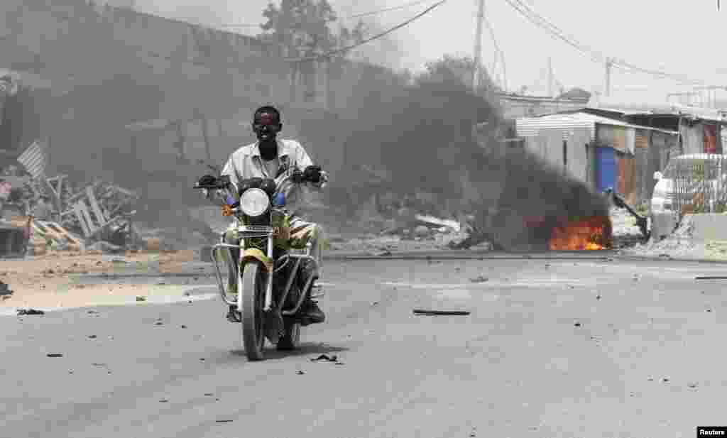 A motorcyclist rides away from the scene of an explosion near the entrance of the airport in Somalia's capital Mogadishu, Feb. 13, 2014.