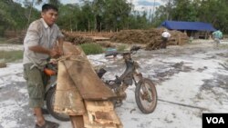 A villager is seen here tying timber to his motorcycle for trading, file photo. 