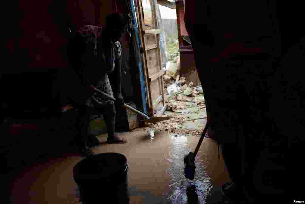 People try to clean the mud at their damaged house after Hurricane Matthew passed Jeremie, Haiti, Oct, 6, 2016.
