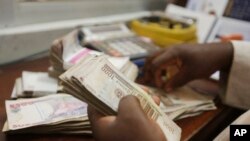 FILE - A money changer counts Nigerian naira currency in Lagos, Nigeria, Oct. 20, 2015.