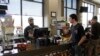 In this photo taken March 20, 2020, Mike Johnston, a clerk at the Maupin Market in tiny Maupin, Oregon, helps a customer while wearing a latex glove to protect himself against the coronavirus.