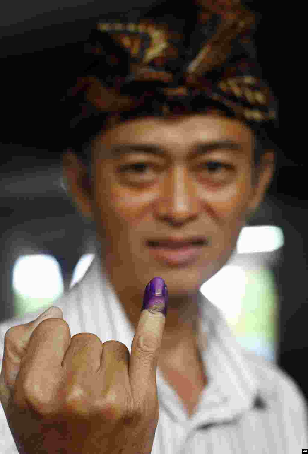 Seorang pemilih menunjukkan jarinya yang bertinta tanda telah memberikan suara dalam pemilihan presiden di Bali (9/7). (AP/Firdia Lisnawati)