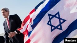 U.S. Secretary of State John Kerry walks past American and Israeli flags at Ben Gurion International Airport in Tel Aviv, Jan. 6, 2014.