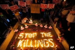 FILE - human rights activists light candles for the victims of extra-judicial killings around the country in the wake of "War on Drugs" campaign by Philippine President Rodrigo Duterte in suburban Quezon city northeast of Manila, Philippines.