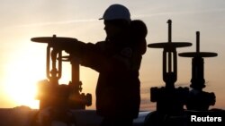 FILE - A worker checks the valve of an oil pipe outside the West Siberian city of Kogalym, Russia, Jan. 25, 2016.