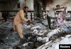 FILE - Relatives inspect the damage after an overnight suicide attack at a mosque in Herat, Afghanistan, Aug. 2, 2017.