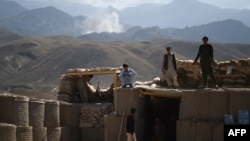 Arhiva - Avganistanski lokalni policajci gledaju kako se uzdiže dim sa mjesta vazdušnog udara na pozicije Islamske države, na kontrolnom punktu u istočnoj provinciji Nangarhar, 7. jula 2018.