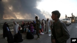 De la fumée s'élèvent alors que les habitants évacuent la ville à Mossoul, Irak, le 18 octobre 2016.