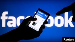FILE - A smartphone user displays a Facebook newsfeed in a May 2, 2013, photo illustration. 