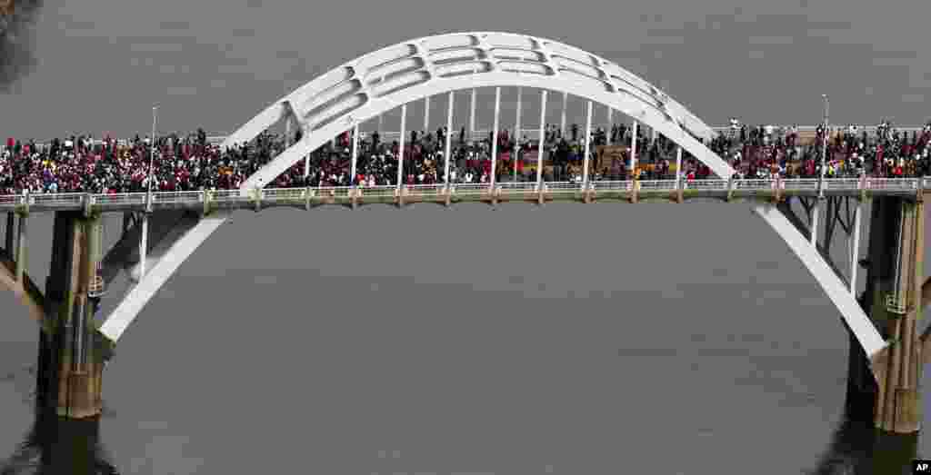 In this aerial photo, crowds of people move in a symbolic walk across the Edmund Pettus Bridge, in Selma, Alabama, March 8, 2015, to marks the 50th anniversary of "Bloody Sunday,' a civil rights march in which protesters were beaten, and tear-gassed by police on the bridge.