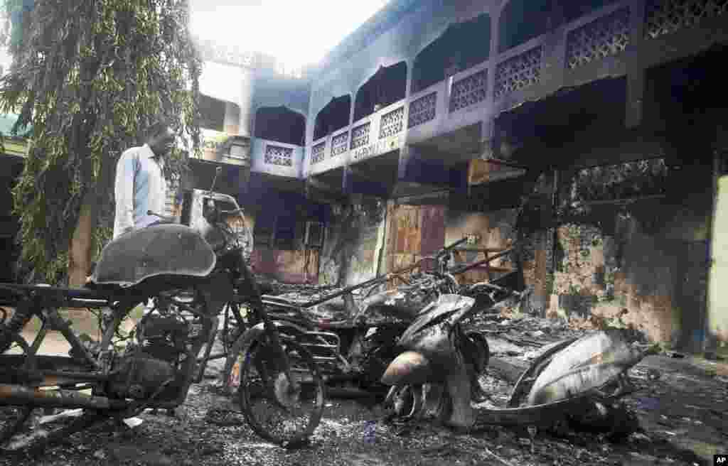 A man observes the remains of destroyed vehicles and buildings in the town of Mpeketoni, Kenya, June 16, 2014. 
