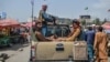 Talibanski borci u vozilu prolaze pijačnom oblašću, između tezgi i lokalnih kupaca, u Kabulu, Afganistan, 17. avgusta 2021.